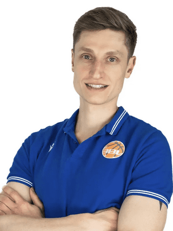 L&auml;chelnder Mann mit kurzen Haaren, tr&auml;gt ein blaues Shirt mit Logo und hat die Arme vor der Brust verschr&auml;nkt.