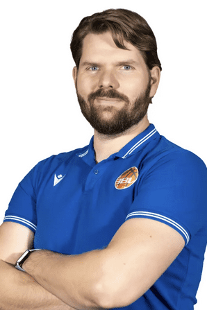 Portr&auml;t eines Mannes mit Bart in blauer Polo-Shirt, l&auml;chelnd mit verschr&auml;nkten Armen vor wei&szlig;em Hintergrund.