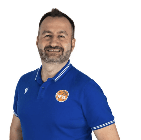 Mann mit Bart in blauer Sportpoloshirt l&auml;chelt vor wei&szlig;em Hintergrund.