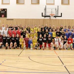 Gruppenfoto von &uuml;ber 40 Handballspielerinnen in verschiedenen Trikots in einer Sporthalle.