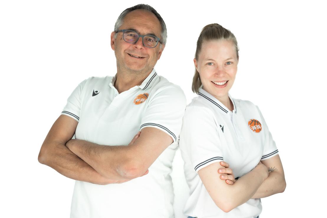 Portrait eines Mannes und einer Frau in wei&szlig;en Polohemden, beide l&auml;cheln und stehen mit verschr&auml;nkten Armen.